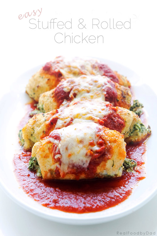 Four stuffed chicken rolls on a plate topped with marinara and mozzarella cheese. 