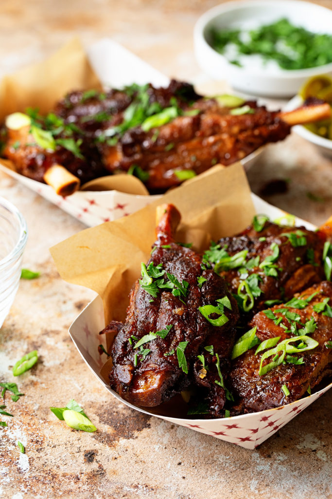 Two paper dishes of pig wings with three in each dish. 