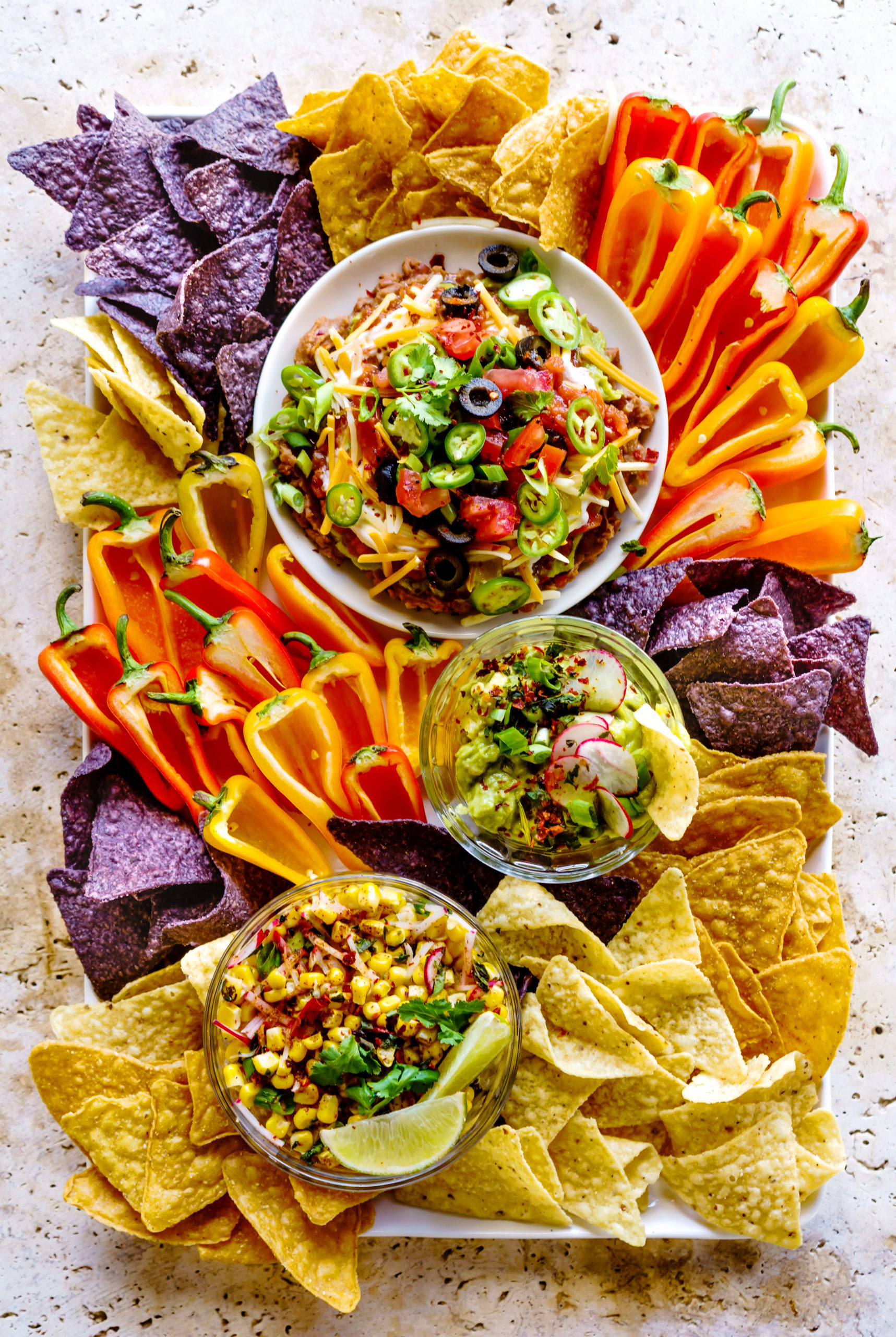 Summer Dip Board with a 7-Layer Bean Dip, Roasted Tomatillo Guacamole and Mexican Corn Dip.